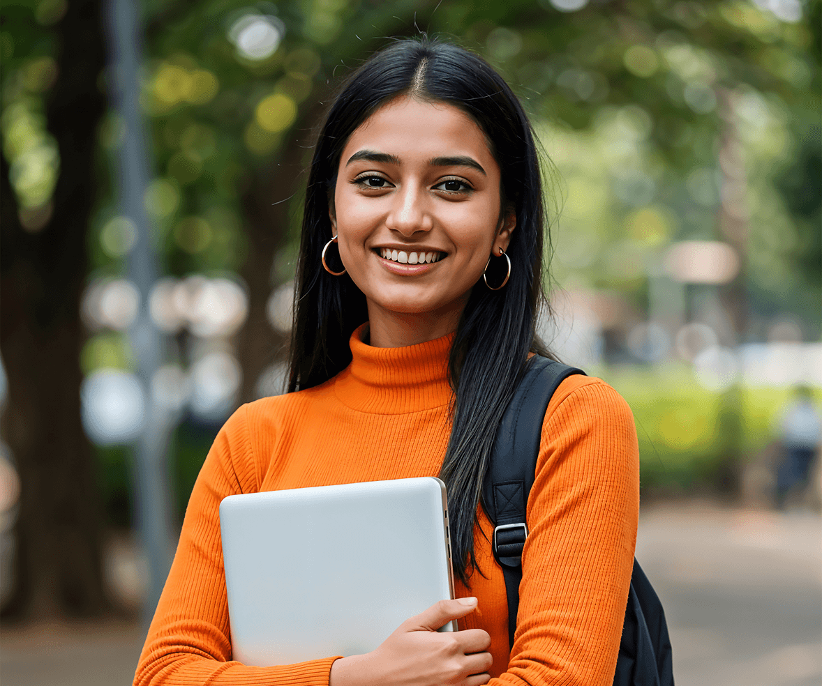 Smiling student holding a laptop on campus
